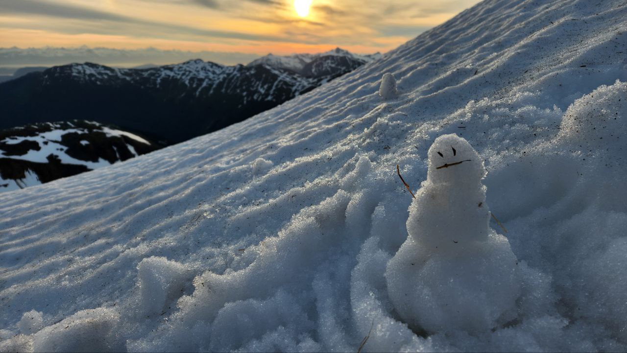 Cute little snowperson that doesn't look particularly happy. Beautiful orange sun-set colors though.